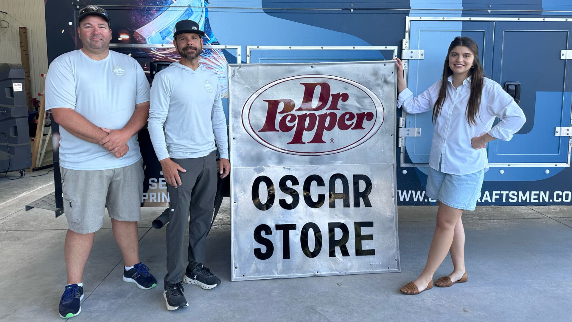 Three staff standing with Dr Pepper sign