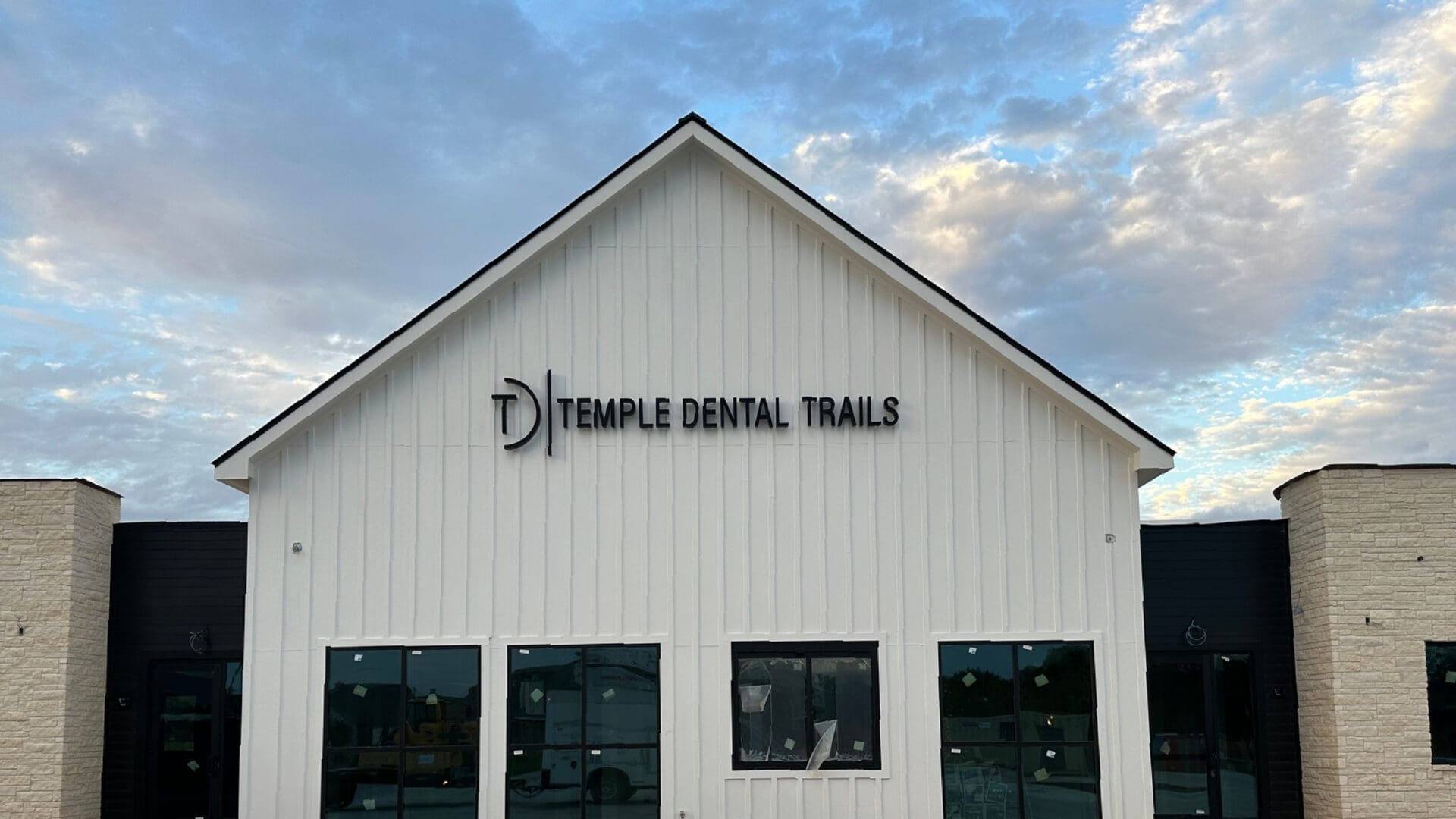 Gabled clinic exterior under blue cloudy sky