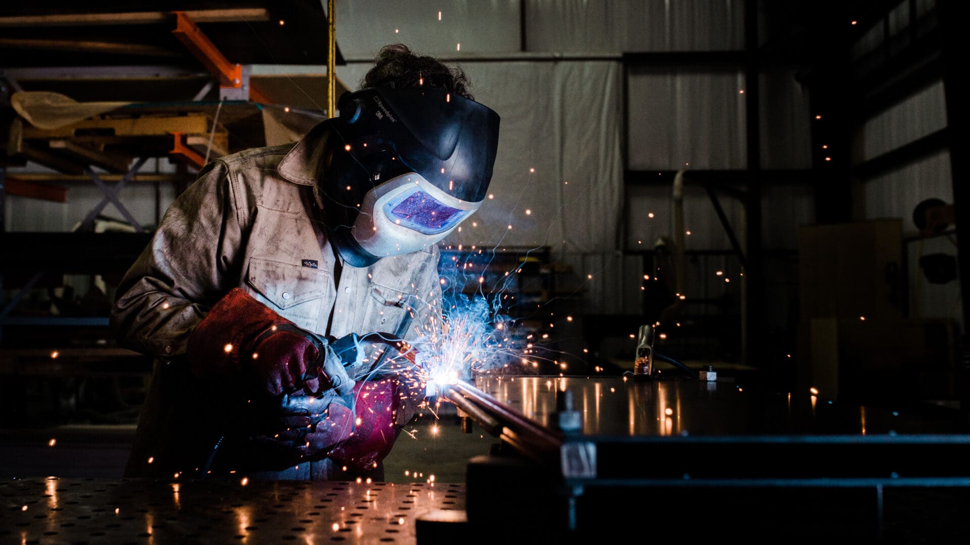 Welder in protective helmet welding metal
